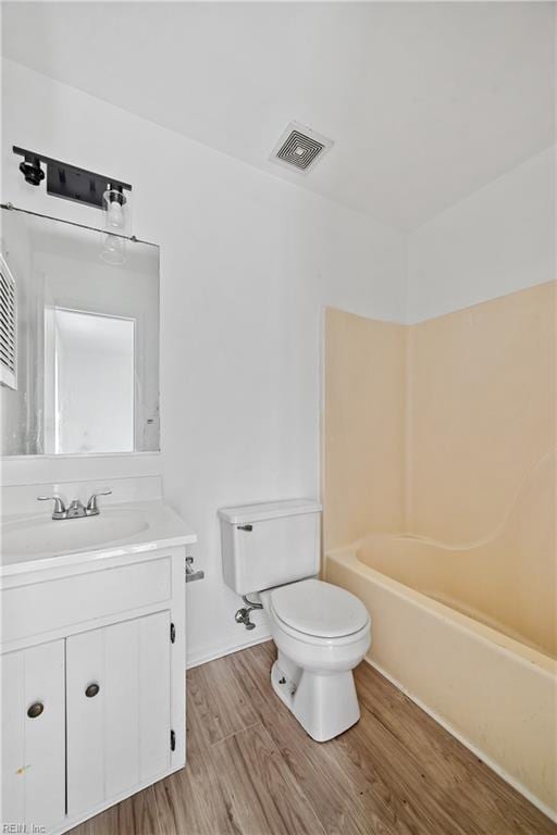 bathroom with toilet, shower / bathing tub combination, vanity, wood finished floors, and visible vents