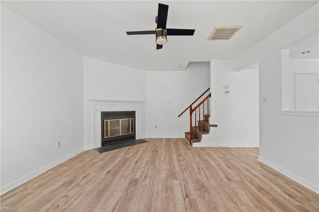 unfurnished living room featuring light wood-style flooring, visible vents, stairway, and a fireplace with flush hearth