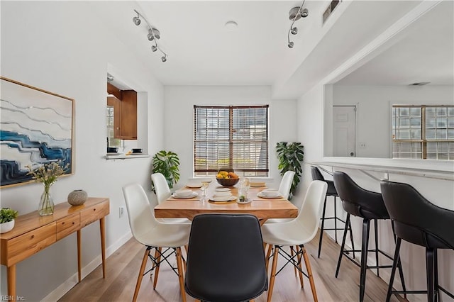 dining room featuring light wood-type flooring, baseboards, and rail lighting