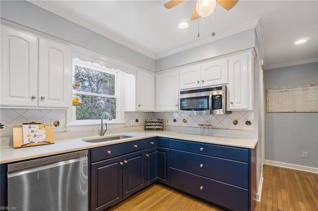 kitchen featuring blue cabinets, stainless steel appliances, light countertops, white cabinetry, and a sink