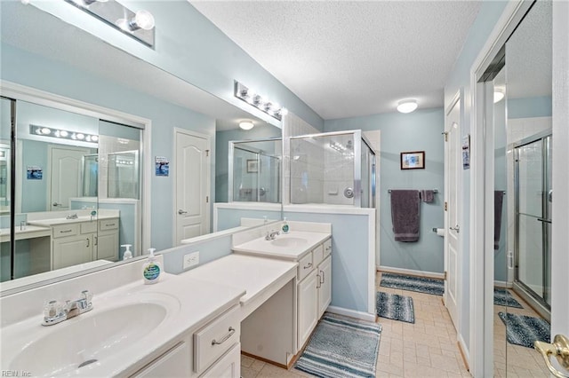 full bathroom with two vanities, a stall shower, a textured ceiling, and a sink