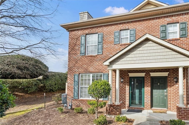 view of front of house with a chimney and brick siding