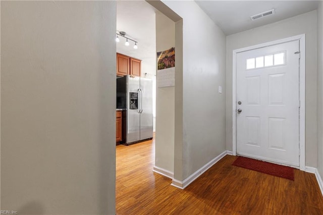 foyer with wood finished floors, baseboards, visible vents, and track lighting