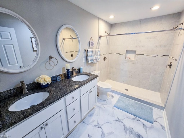 bathroom featuring toilet, marble finish floor, a shower stall, and a sink