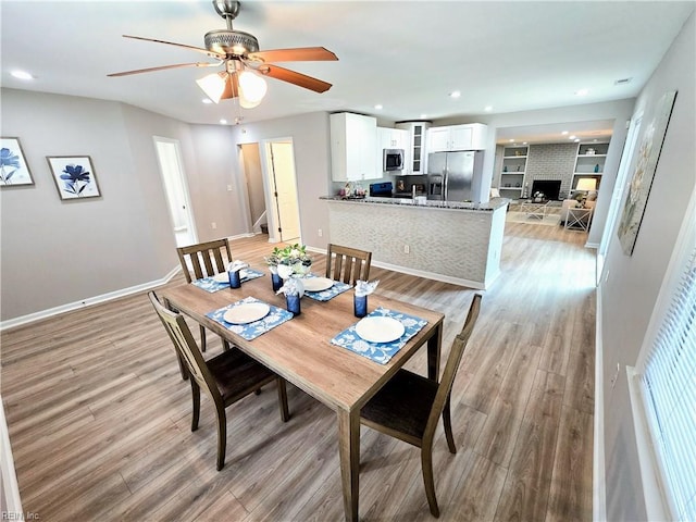 dining area with baseboards, light wood-type flooring, built in shelves, a fireplace, and recessed lighting