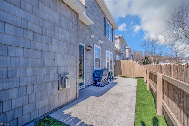 view of home's exterior featuring a wall mounted AC, a patio area, and a fenced backyard