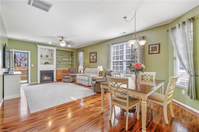 dining space featuring a glass covered fireplace, visible vents, and wood finished floors