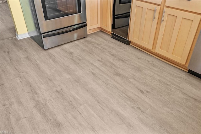 room details featuring light brown cabinetry, light wood finished floors, and stove