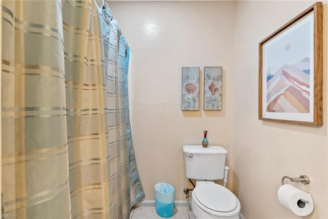 bathroom featuring curtained shower, baseboards, and toilet