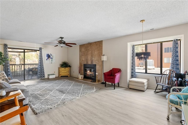 living area featuring a fireplace, a textured ceiling, and wood finished floors