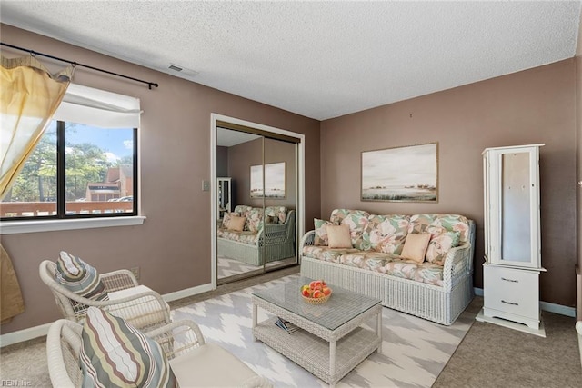 carpeted living room featuring visible vents, baseboards, and a textured ceiling