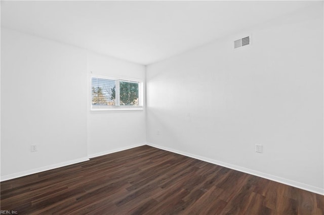 spare room featuring baseboards, visible vents, and dark wood-type flooring