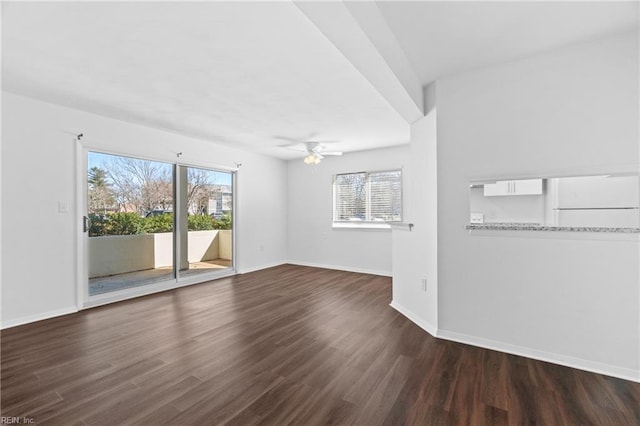 unfurnished living room with dark wood-style floors, baseboards, and a wealth of natural light