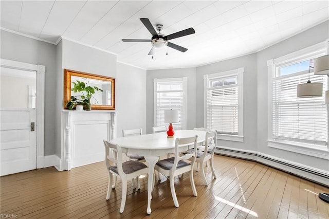 dining room featuring a ceiling fan, ornamental molding, baseboard heating, and wood finished floors