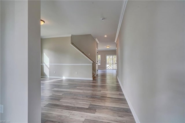 hall featuring light wood-type flooring, baseboards, and ornamental molding