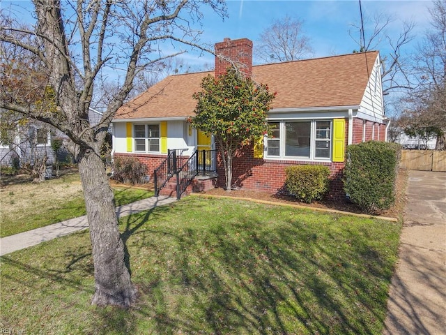 view of front of house featuring a chimney, a front lawn, and brick siding