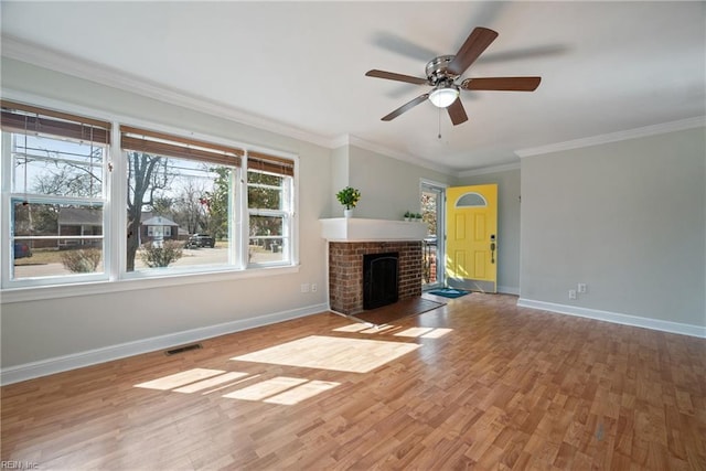 unfurnished living room with baseboards, visible vents, wood finished floors, crown molding, and a fireplace