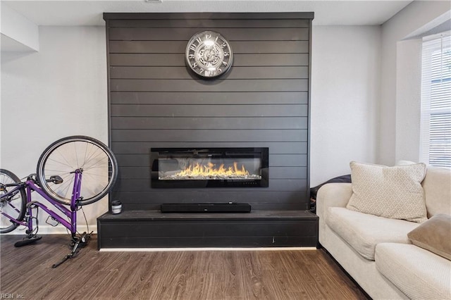 living area featuring dark wood-type flooring and a large fireplace