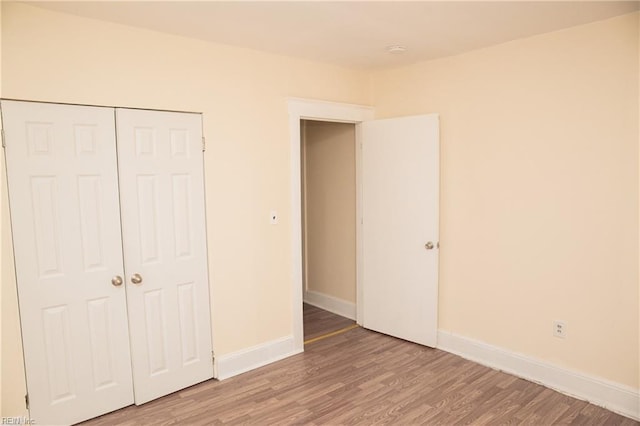 unfurnished bedroom with a closet, wood finished floors, and baseboards
