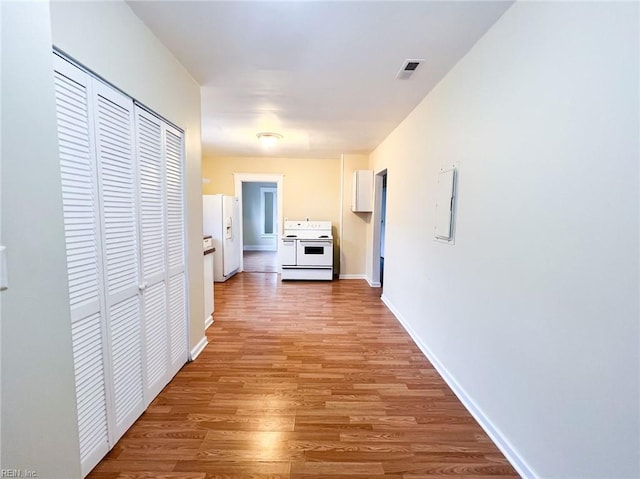 hall featuring light wood finished floors, electric panel, visible vents, and baseboards