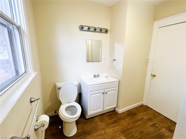 half bath featuring vanity, wood finished floors, toilet, and baseboards