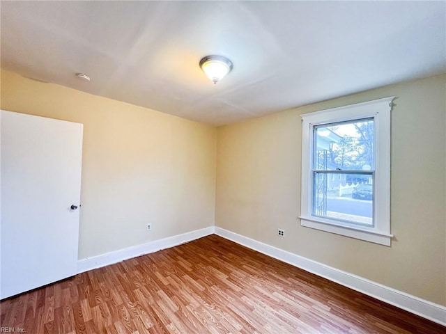 spare room with baseboards and wood finished floors