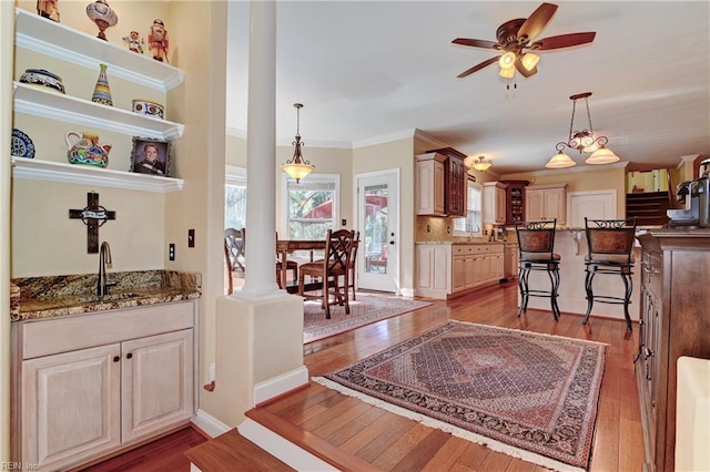 interior space with light wood finished floors, dark stone counters, hanging light fixtures, open shelves, and a sink