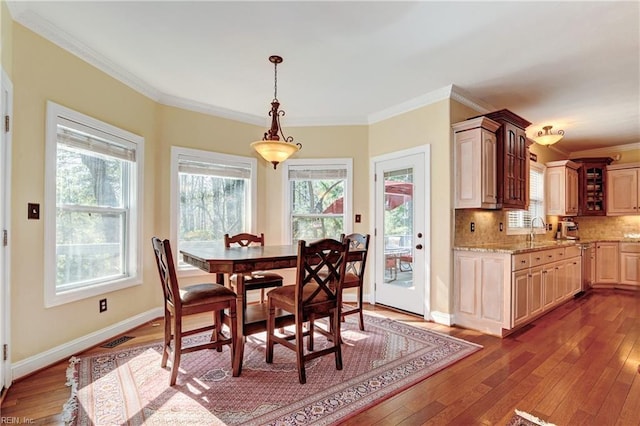 dining area with a healthy amount of sunlight, crown molding, and dark wood-type flooring