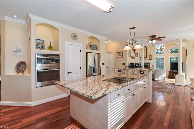 kitchen with decorative columns, a kitchen island, appliances with stainless steel finishes, hanging light fixtures, and white cabinetry