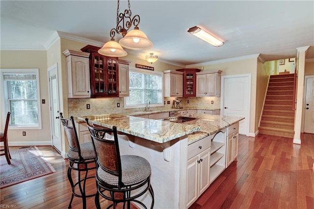 kitchen featuring dark wood-style flooring, a center island, open shelves, a kitchen bar, and glass insert cabinets