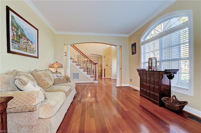 living room featuring stairway, wood finished floors, visible vents, and ornate columns