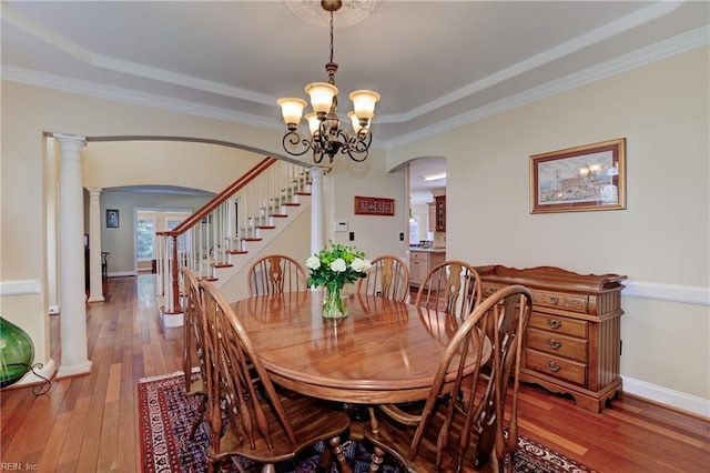 dining space with baseboards, arched walkways, wood finished floors, stairs, and a notable chandelier