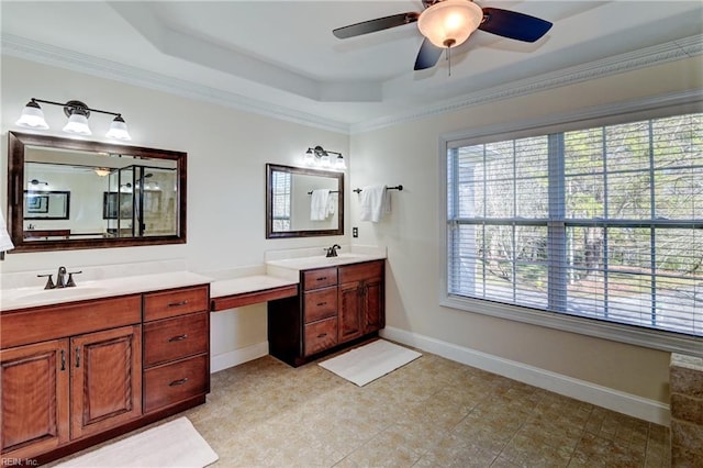 full bath with a raised ceiling, two vanities, a sink, and baseboards