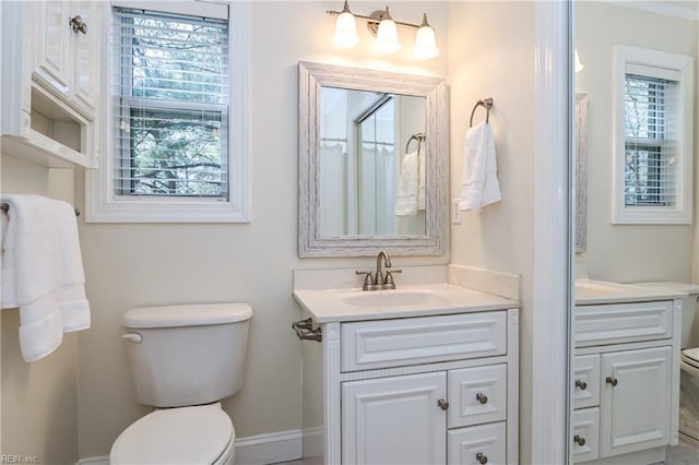 bathroom with plenty of natural light, vanity, toilet, and baseboards