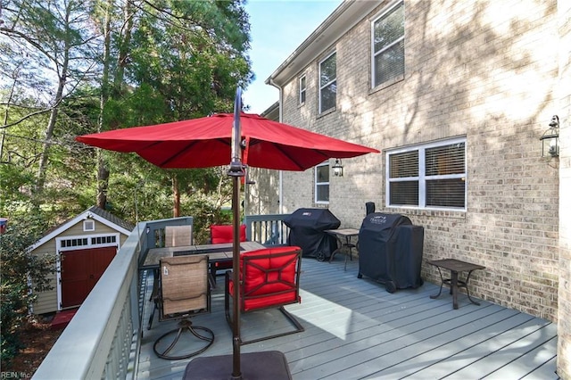 deck with a storage shed, outdoor dining area, grilling area, and an outdoor structure