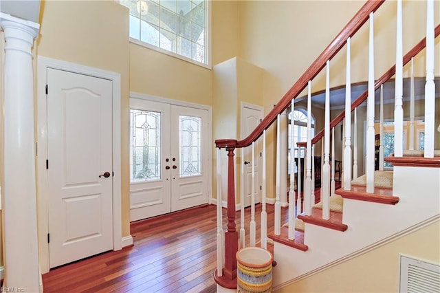 foyer entrance with visible vents, a towering ceiling, stairway, wood finished floors, and french doors