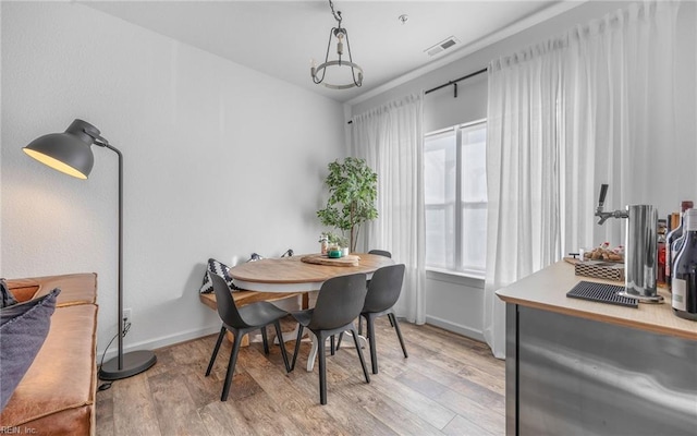 dining space featuring baseboards, visible vents, and light wood finished floors