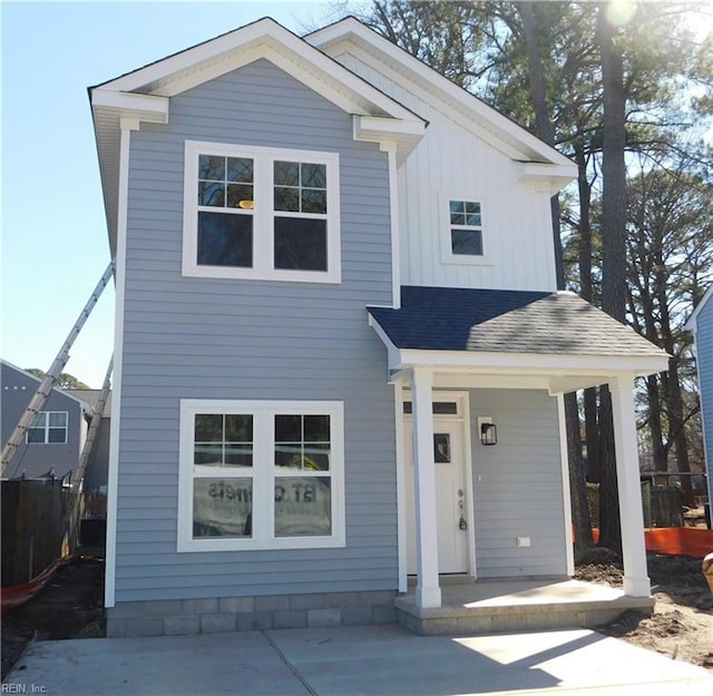 view of front of property with fence, a porch, board and batten siding, and roof with shingles