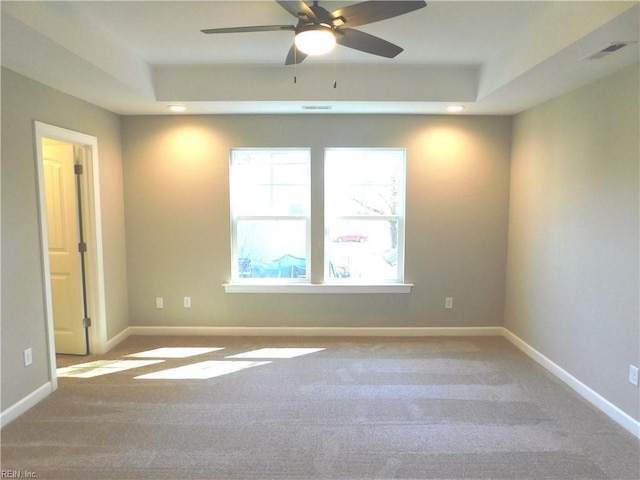 empty room with carpet, a raised ceiling, and baseboards