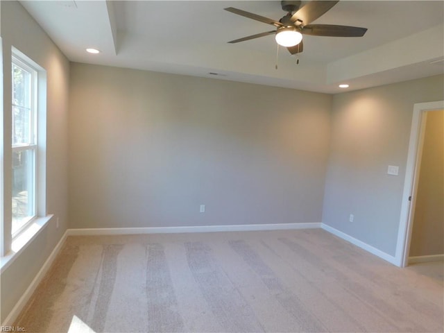 empty room with baseboards, a raised ceiling, and a wealth of natural light