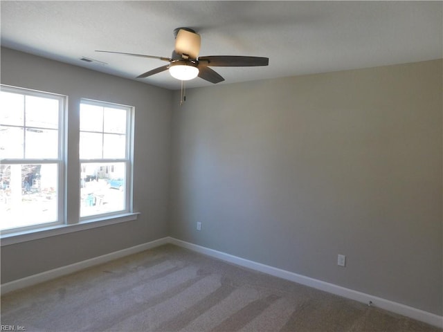 empty room with a ceiling fan, light colored carpet, and baseboards