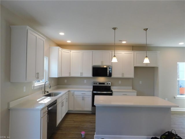 kitchen with stainless steel appliances, a center island, white cabinets, and a sink