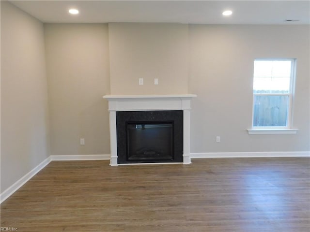 unfurnished living room featuring wood finished floors, recessed lighting, a glass covered fireplace, and baseboards