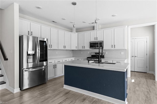 kitchen featuring tasteful backsplash, appliances with stainless steel finishes, light countertops, white cabinetry, and pendant lighting