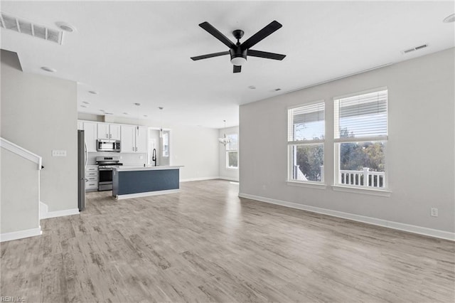 unfurnished living room featuring ceiling fan, light wood-style flooring, a sink, and visible vents