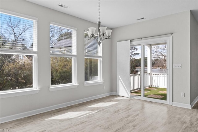 unfurnished dining area featuring a notable chandelier, wood finished floors, visible vents, and baseboards