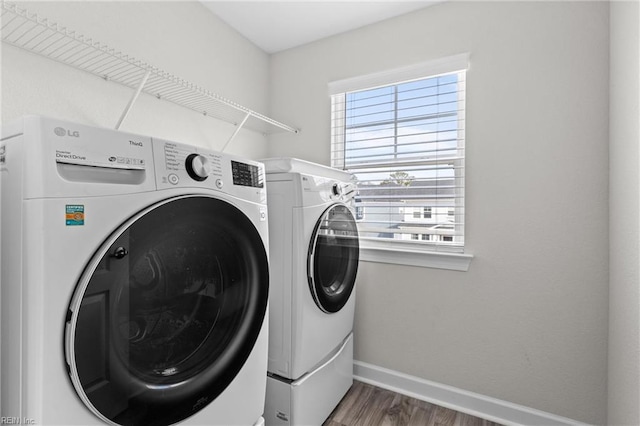 laundry area featuring laundry area, baseboards, wood finished floors, and washing machine and clothes dryer