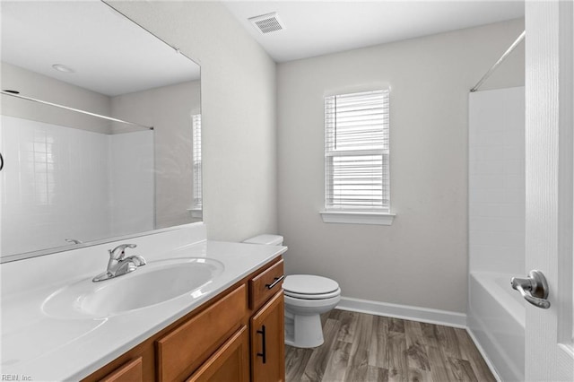 bathroom featuring baseboards, visible vents, toilet, wood finished floors, and vanity