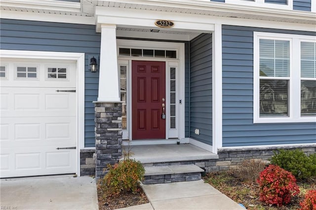 view of exterior entry featuring a garage and stone siding