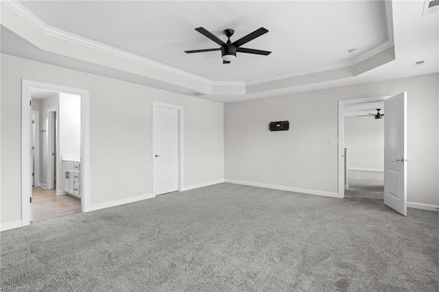 unfurnished bedroom with baseboards, visible vents, ornamental molding, a tray ceiling, and carpet floors